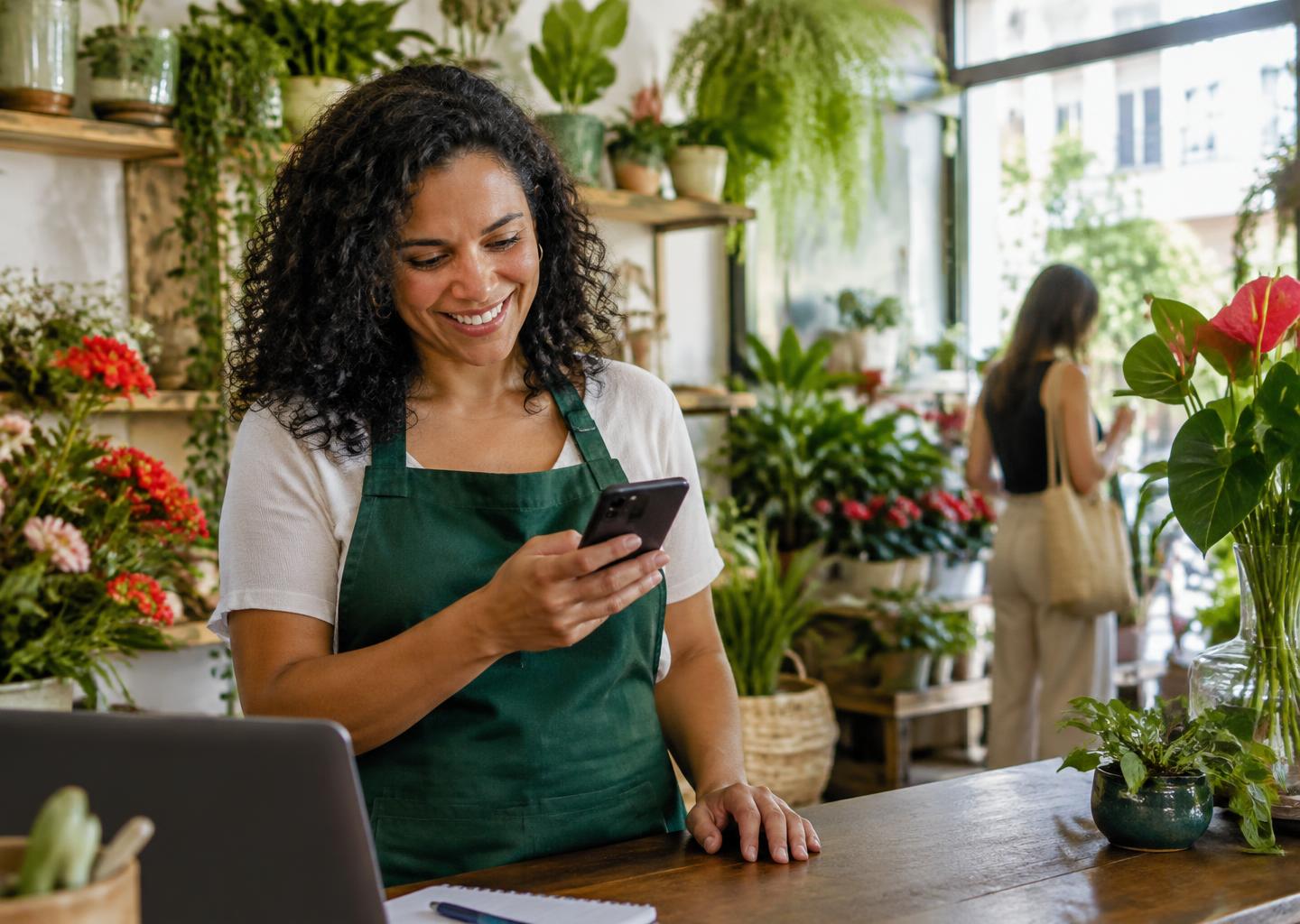 Dona de uma floricultura lendo uma mensagem no celular